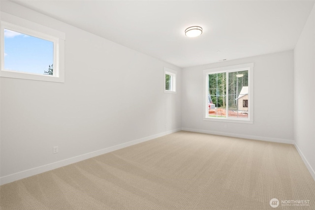 unfurnished room featuring light carpet and baseboards