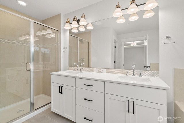 bathroom featuring a shower stall, tasteful backsplash, a sink, and tile patterned floors