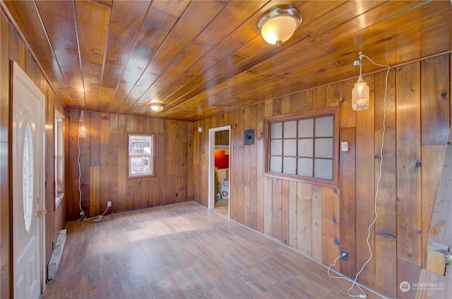 unfurnished room with wooden walls, wood ceiling, and wood-type flooring