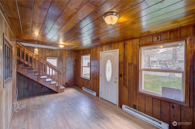 foyer entrance with a baseboard radiator, hardwood / wood-style floors, and wood walls