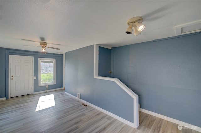 spare room with ceiling fan, light hardwood / wood-style floors, and a textured ceiling