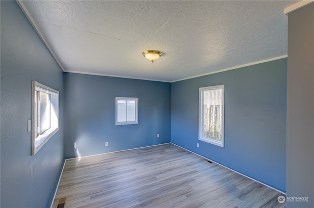 unfurnished room featuring light hardwood / wood-style floors, a textured ceiling, a healthy amount of sunlight, and ornamental molding