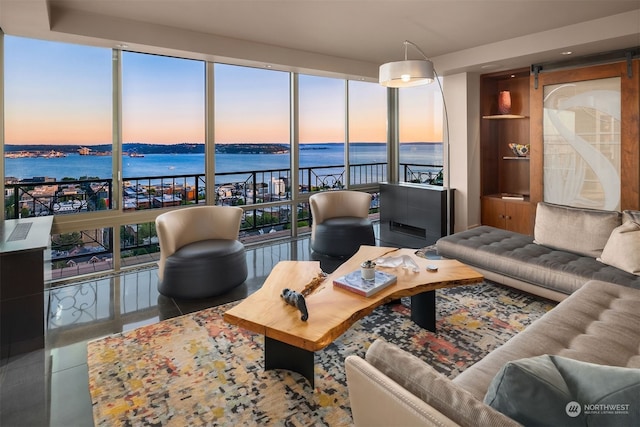 living room with a barn door, a water view, tile flooring, and a wealth of natural light