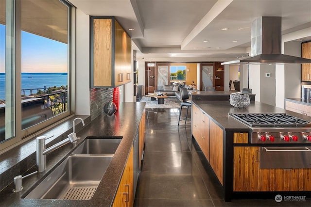 kitchen featuring dark tile floors, sink, island exhaust hood, backsplash, and a water view