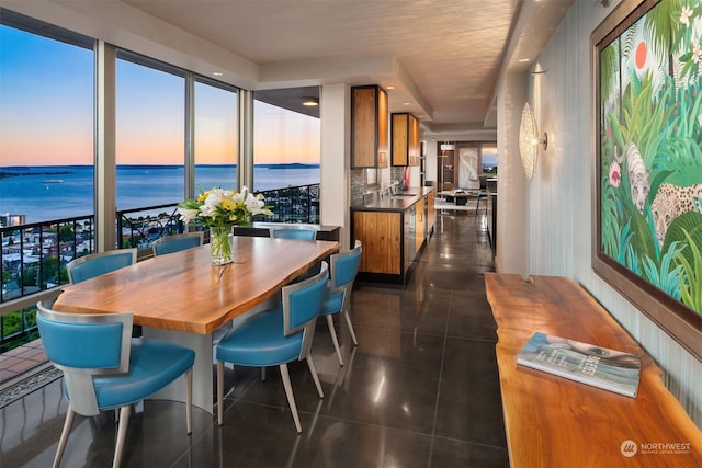 dining area with a water view and dark tile flooring