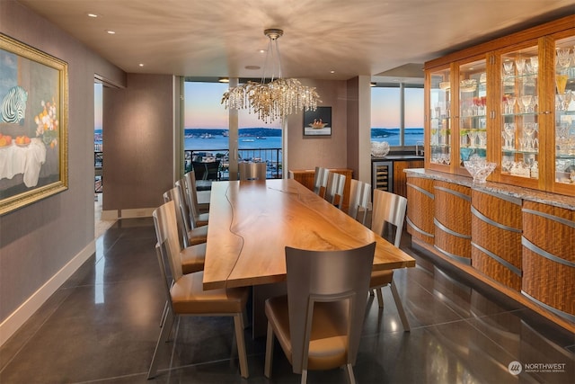 dining space featuring floor to ceiling windows, a notable chandelier, a water view, beverage cooler, and bar