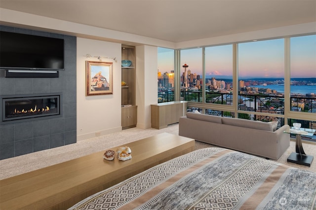 interior space featuring light carpet, a water view, and a tiled fireplace