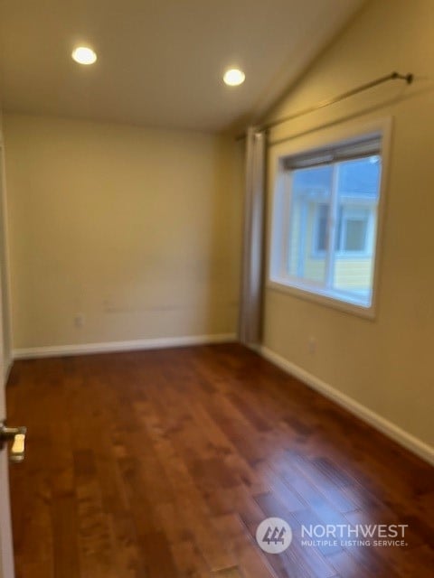 spare room featuring dark hardwood / wood-style flooring and vaulted ceiling