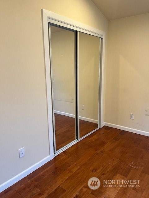 unfurnished bedroom with dark hardwood / wood-style flooring, a closet, and lofted ceiling