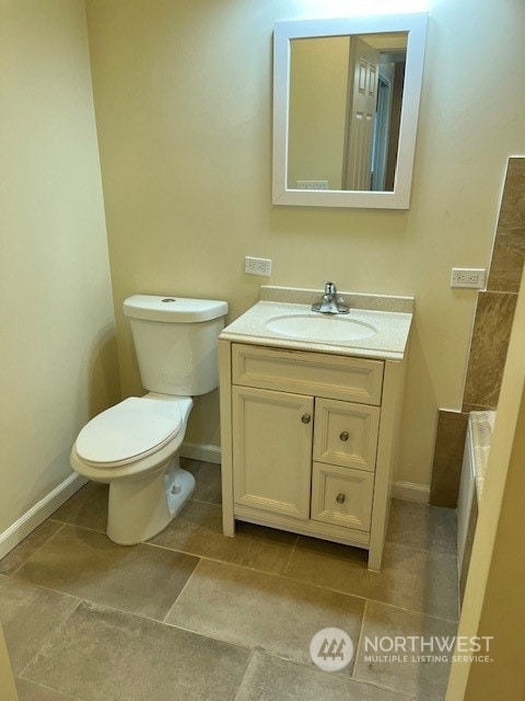 bathroom featuring toilet, tile flooring, and vanity