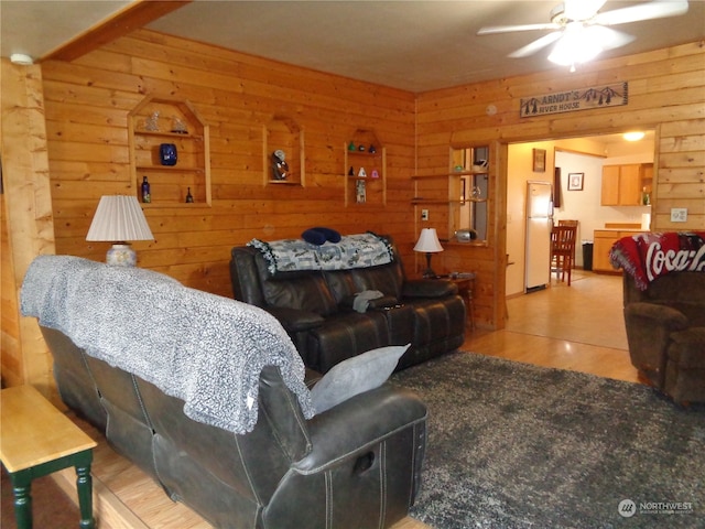 living room with ceiling fan, wood walls, and light hardwood / wood-style flooring