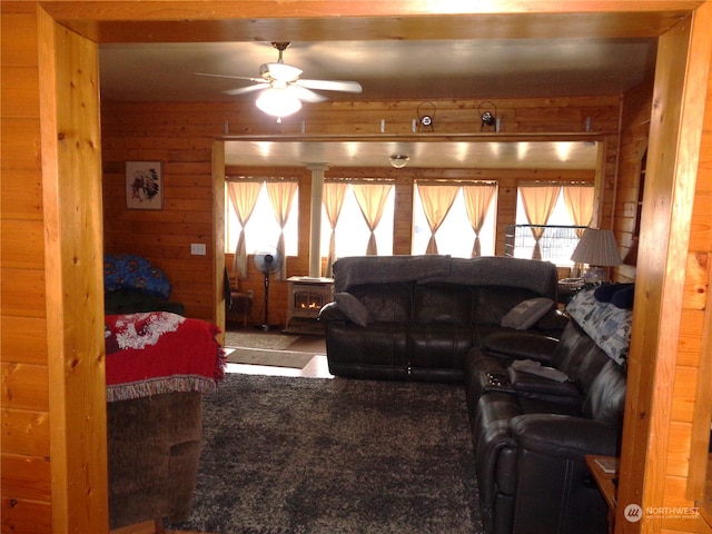 living room featuring wooden walls, beam ceiling, ceiling fan, and carpet floors