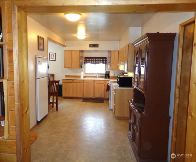 kitchen with white refrigerator, sink, and light tile floors