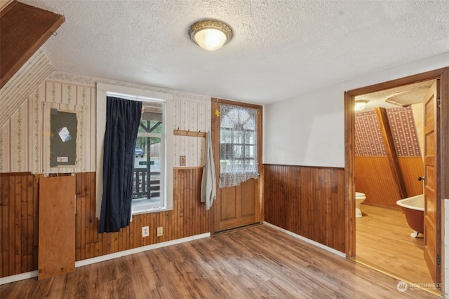 foyer featuring hardwood / wood-style floors, wood walls, and a textured ceiling