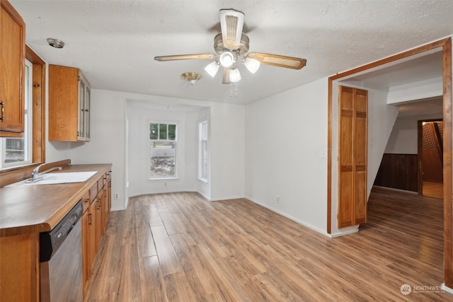 kitchen with a textured ceiling, dishwasher, sink, and light hardwood / wood-style flooring