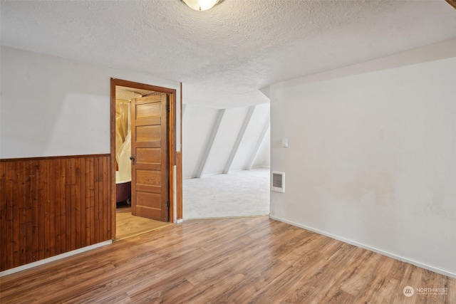 bonus room featuring hardwood / wood-style floors, a textured ceiling, and wood walls