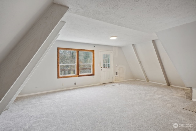 additional living space featuring light carpet and a textured ceiling