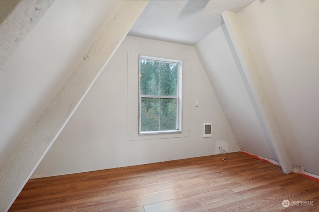 additional living space featuring vaulted ceiling and light wood-type flooring