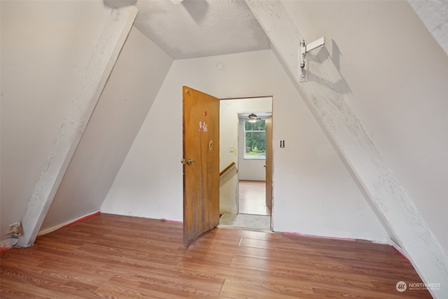 additional living space with light hardwood / wood-style floors and lofted ceiling