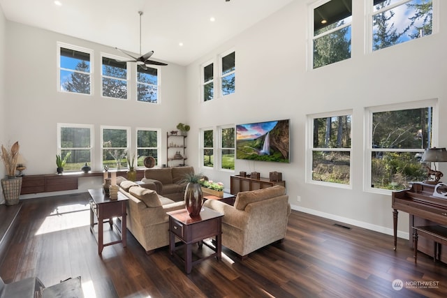 living room featuring ceiling fan, a high ceiling, and dark hardwood / wood-style flooring