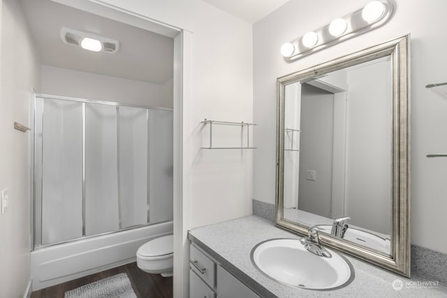 full bathroom with combined bath / shower with glass door, toilet, vanity, and hardwood / wood-style floors