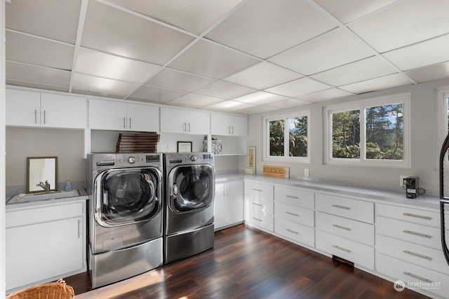 clothes washing area with sink, dark wood-type flooring, cabinets, and washing machine and dryer