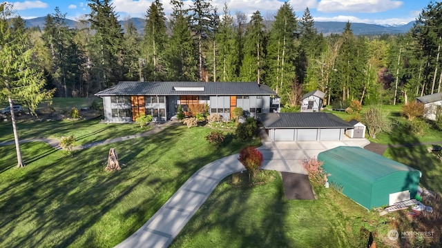 exterior space with a mountain view, a garage, a front lawn, and an outdoor structure