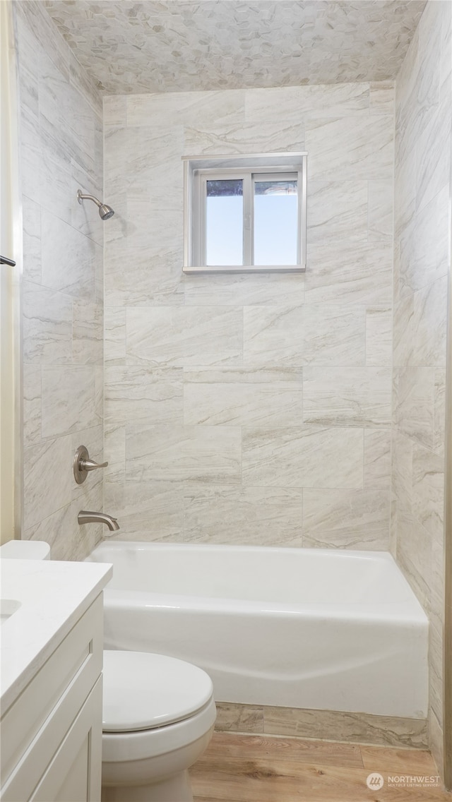 full bathroom with vanity, tiled shower / bath combo, toilet, and hardwood / wood-style floors