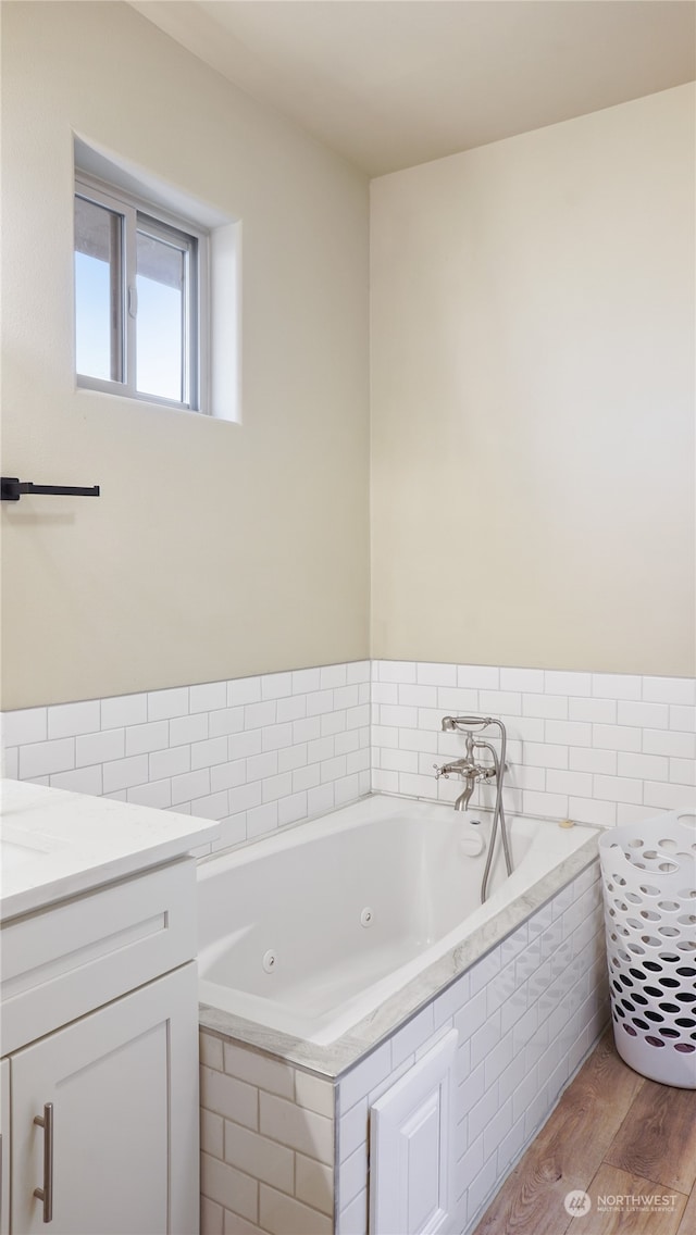 bathroom with vanity, hardwood / wood-style flooring, and tiled tub