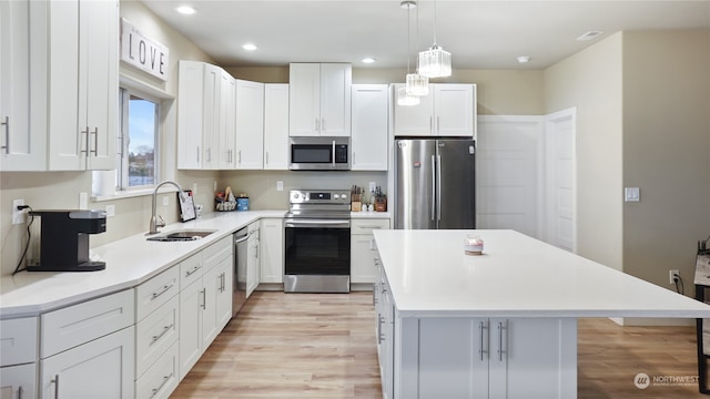 kitchen with a center island, appliances with stainless steel finishes, pendant lighting, and white cabinetry