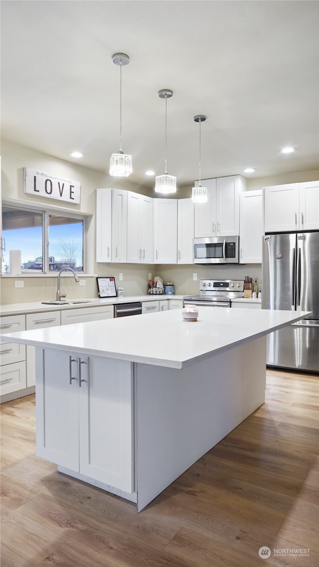 kitchen featuring light hardwood / wood-style flooring, white cabinetry, stainless steel appliances, and a kitchen island