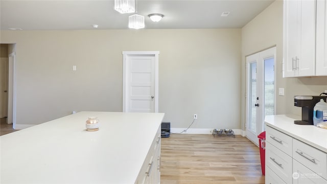 kitchen with white cabinets, decorative light fixtures, and light wood-type flooring