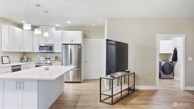 kitchen featuring washer / dryer, white cabinetry, light wood-type flooring, pendant lighting, and stainless steel appliances