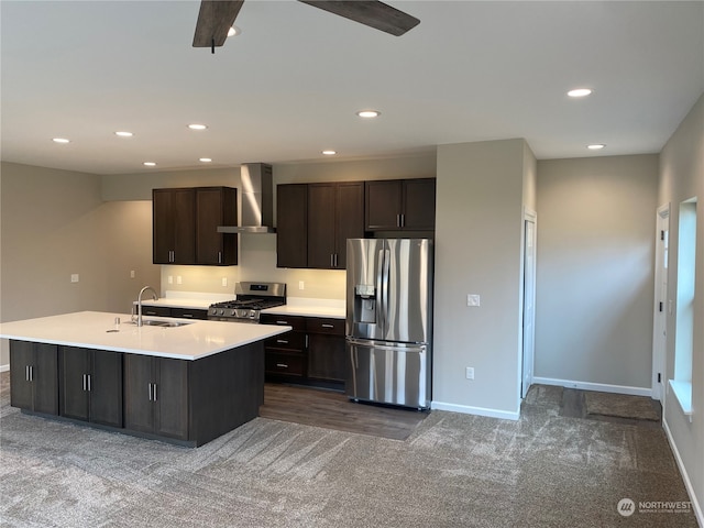 kitchen with carpet floors, a kitchen island with sink, sink, appliances with stainless steel finishes, and wall chimney range hood