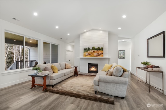 living room featuring a large fireplace, lofted ceiling, and light wood-type flooring