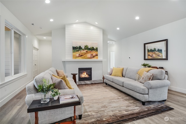 living room with hardwood / wood-style floors, a large fireplace, and vaulted ceiling