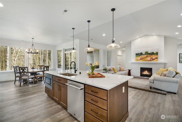 kitchen featuring light wood-type flooring, a large fireplace, stainless steel appliances, sink, and decorative light fixtures