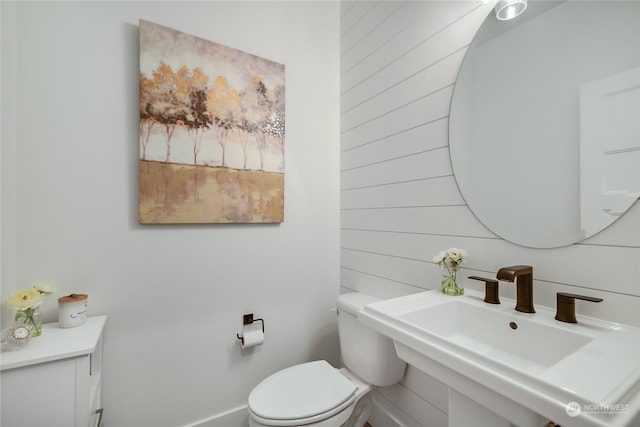 bathroom with wooden walls, sink, and toilet