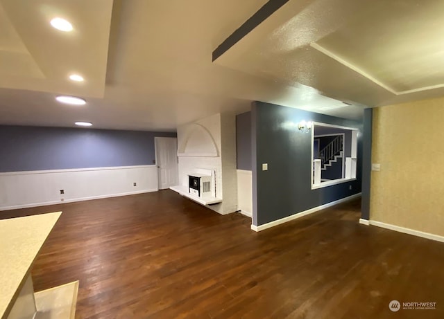 bonus room featuring dark wood-type flooring and a large fireplace