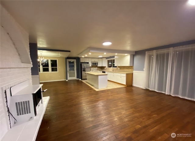 unfurnished living room with an inviting chandelier, dark hardwood / wood-style floors, and sink