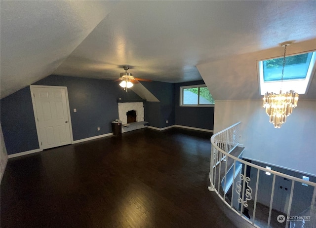 bonus room with lofted ceiling, a textured ceiling, dark hardwood / wood-style floors, and ceiling fan with notable chandelier