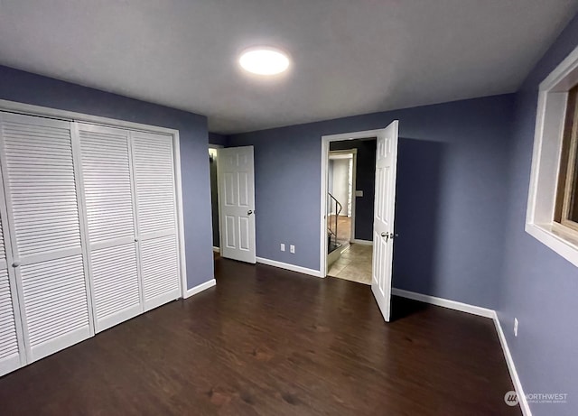 unfurnished bedroom with a closet and dark hardwood / wood-style floors