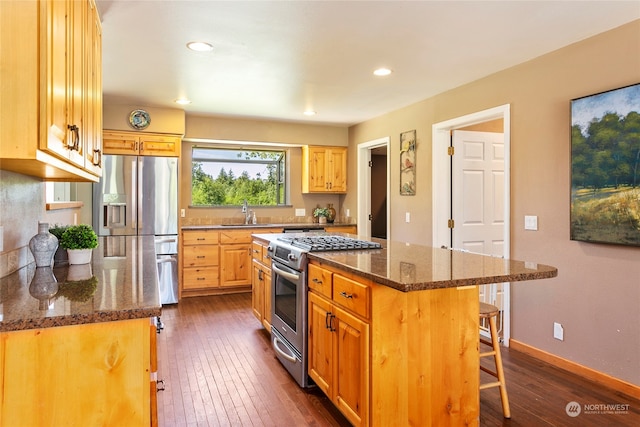 kitchen featuring appliances with stainless steel finishes, dark stone countertops, a center island, and dark hardwood / wood-style floors