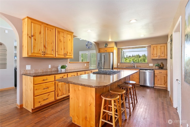 kitchen with dark hardwood / wood-style flooring, a kitchen island, appliances with stainless steel finishes, and sink