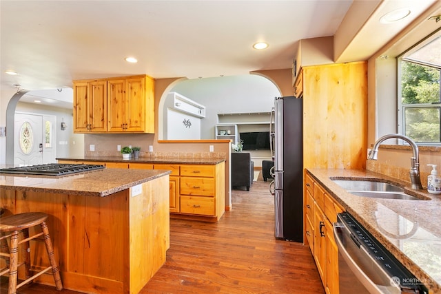 kitchen featuring dark hardwood / wood-style floors, stainless steel appliances, sink, and light stone countertops