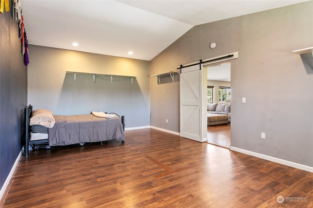 bedroom featuring a barn door, lofted ceiling, and dark hardwood / wood-style flooring