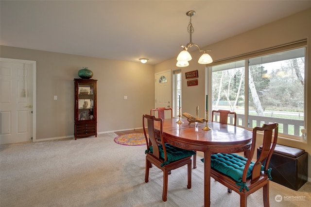 dining space featuring light carpet and an inviting chandelier