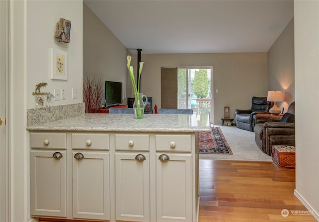 kitchen featuring light hardwood / wood-style flooring, light stone countertops, and kitchen peninsula