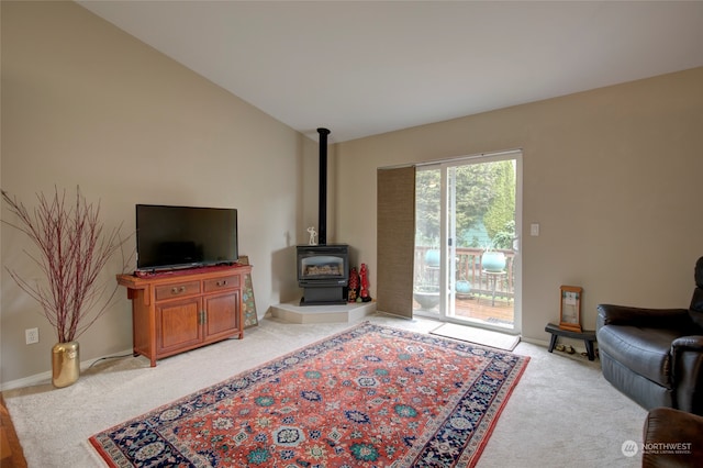 living room featuring lofted ceiling, light colored carpet, and a wood stove