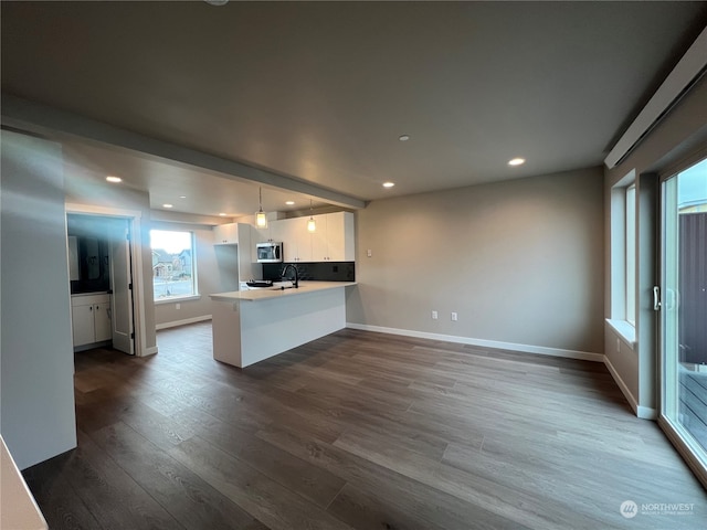 kitchen with white cabinetry, sink, hanging light fixtures, dark hardwood / wood-style flooring, and kitchen peninsula